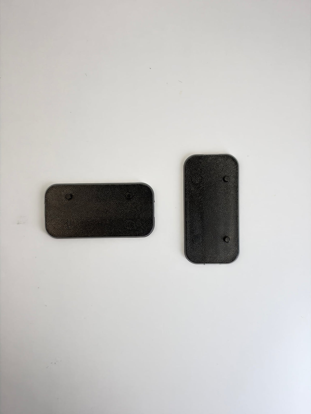 Two black rectangular plastic Action Figure Stands with two foot pegs each, shown on a plain light background.