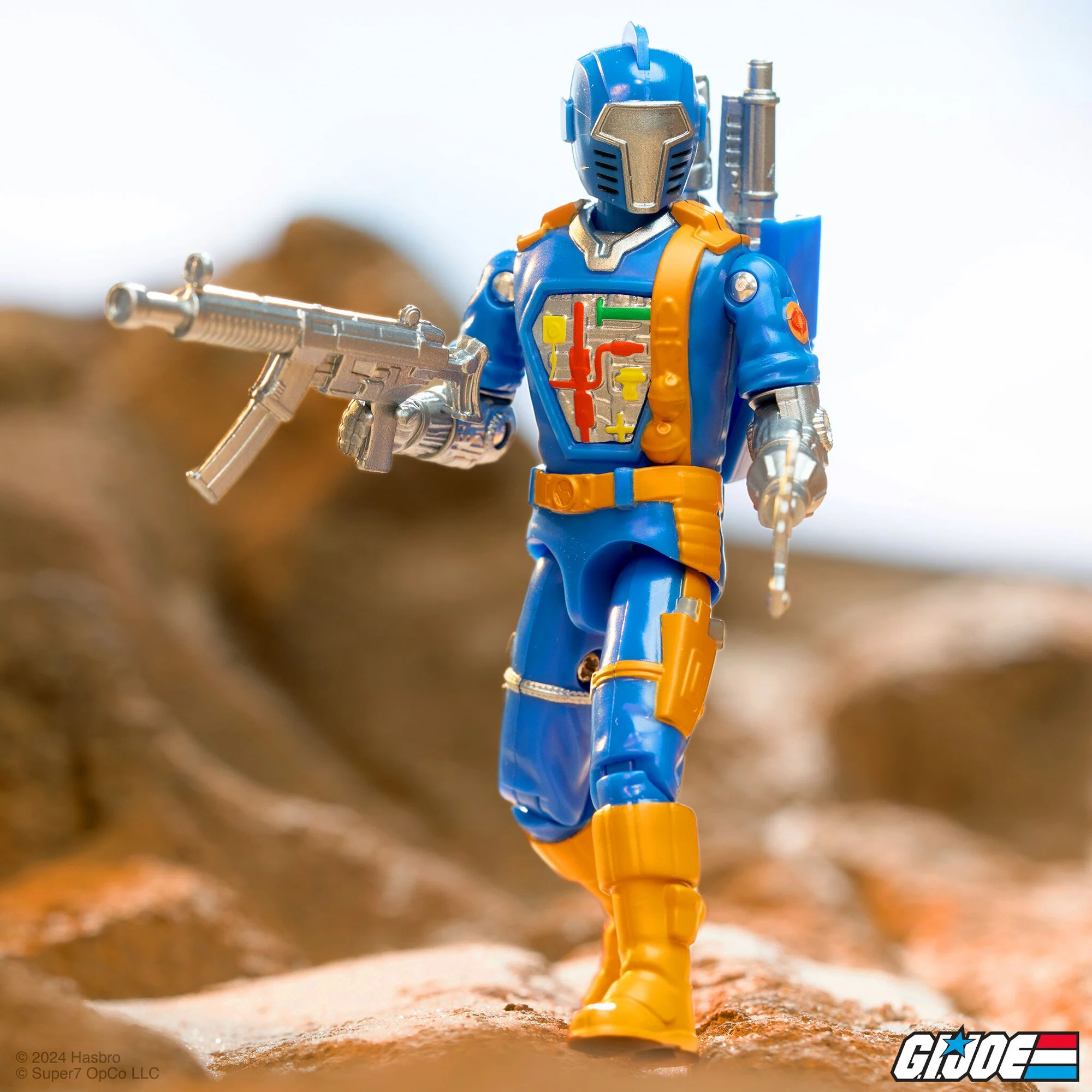 Cobra B.A.T. Comic Blue ReAction+ figure action pose with blaster on rocky terrain – Super7 G.I. Joe